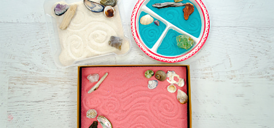 An image of mini zen gardens with pink, white and blue coloured sand decorated with shells